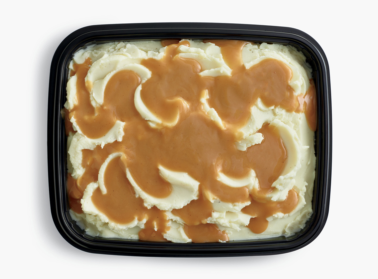 Open catering container of mashed potatoes with gravy